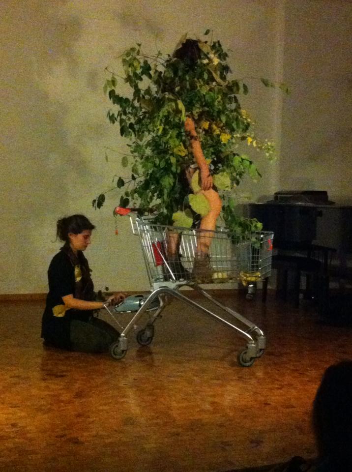 shelley kneeling at typewriter and sara as tree-performer in shopping cart